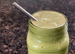 close up of coffee milkshake in glass with metal straw