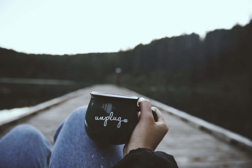 hand holding coffee cup that reads "unplug" outside