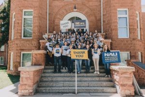 NAU faculty, staff and students gathered with a sign that reads 'Thank you' for NAU Giving Day